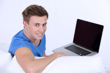 beyaz zemin üzerinde laptop ile kanepede oturan adamı