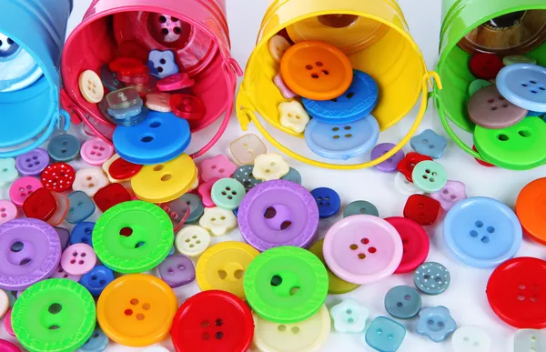 Colorful buttons strewn from buckets close-up — Stok fotoğraf