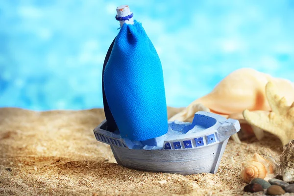 Blue toy ship on sand, on blue background — Stock Photo, Image