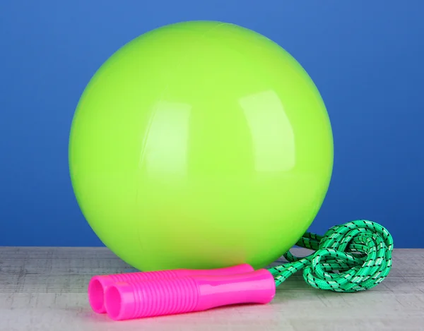 Bright green ball and rope on table on blue background — Stock Photo, Image