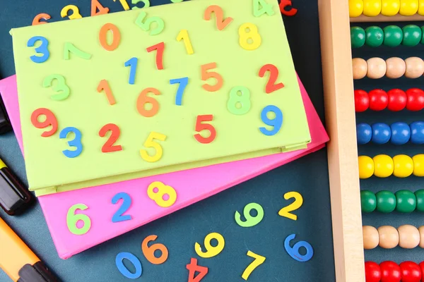 Färgstarka nummer, abacus, böcker och markörer på skolan skrivbord bakgrund — Stockfoto