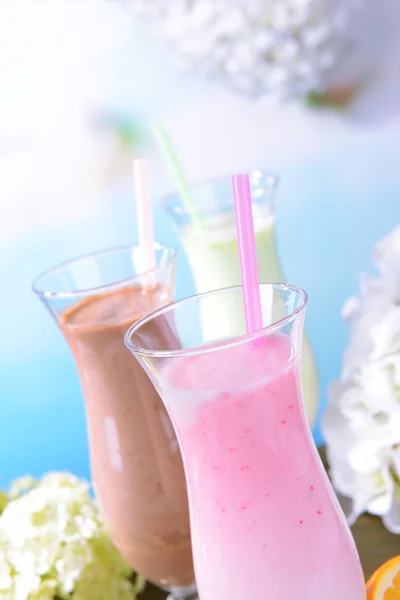 Susu kocok dengan buah-buahan di atas meja pada latar belakang biru muda — Stok Foto