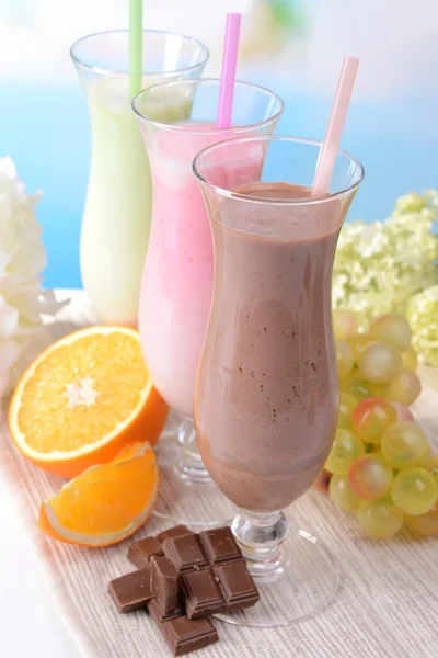 Milk shakes avec des fruits sur la table sur fond bleu clair — Photo