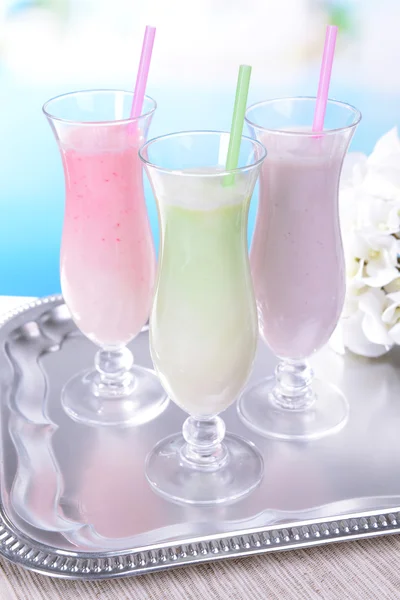 Milk shakes on table on light blue background — Stock Photo, Image