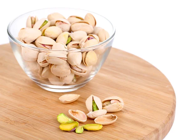 Pistacchi in ciotola di vetro su cavalletto di legno isolato su bianco — Foto Stock