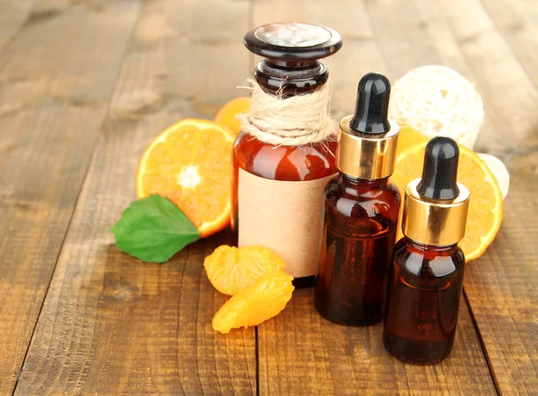 Tangerine essential oil and tangerines on wooden table — Stock Photo, Image