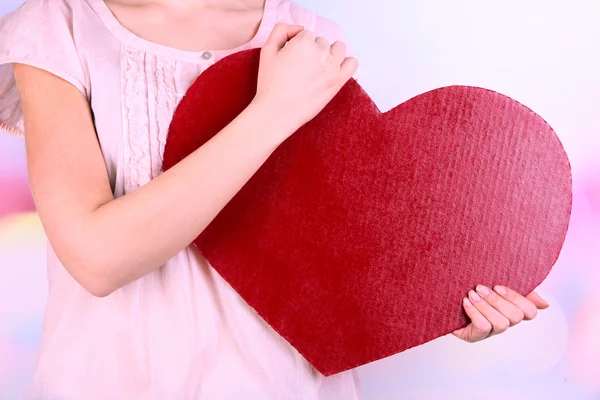 Mujer sosteniendo gran corazón rojo sobre fondo brillante —  Fotos de Stock