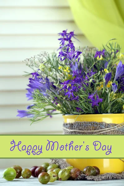 Beautiful bouquet of wildflowers in cup and berries on wooden table — Stock Photo, Image