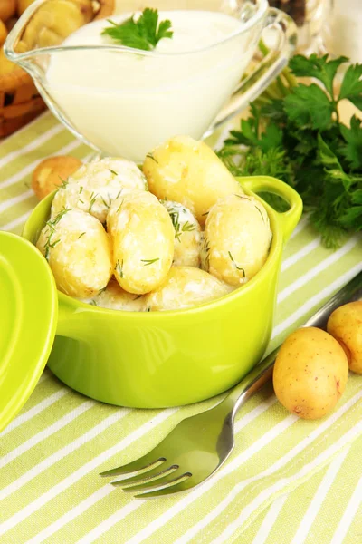 Batatas jovens macias com nata azeda e ervas na panela na mesa de madeira close-up — Fotografia de Stock