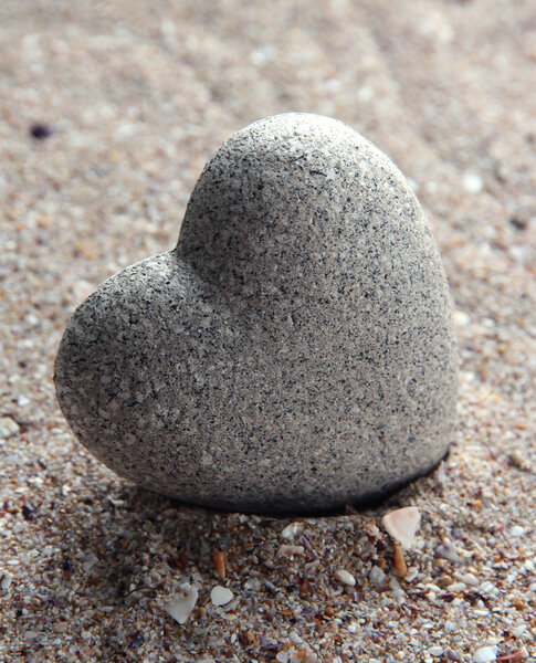 Grey stone in shape of heart, on sand background