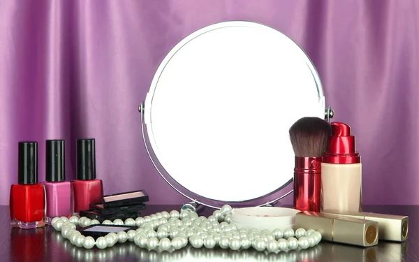 Espejo de mesa redonda con cosméticos y chaplet sobre tabla sobre fondo de tela —  Fotos de Stock