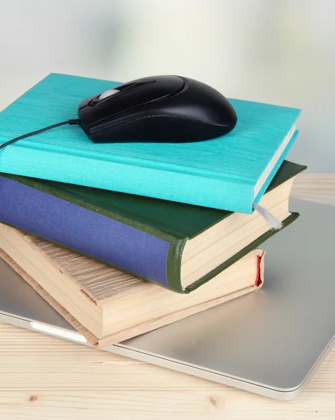 Mouse de computador em livros e notebook em mesa de madeira no fundo do quarto — Fotografia de Stock