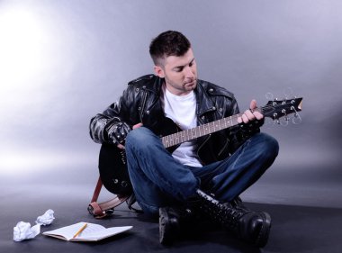 genç müzisyen gri arka plan üzerinde gitar çalmak