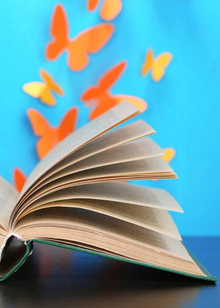Öppnade boken på träbord på fjärilar bakgrund — Stockfoto