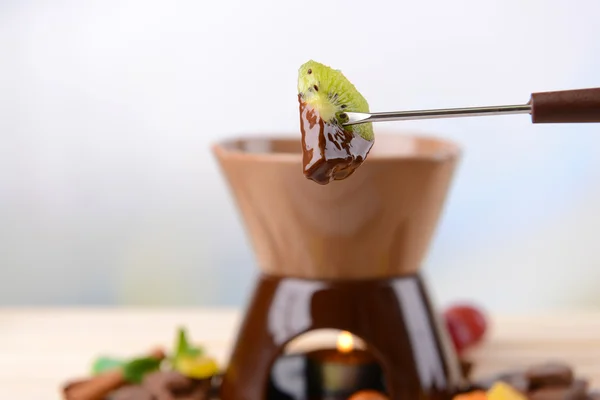 Fonduta al cioccolato con frutta, su tavolo di legno, su fondo chiaro — Foto Stock