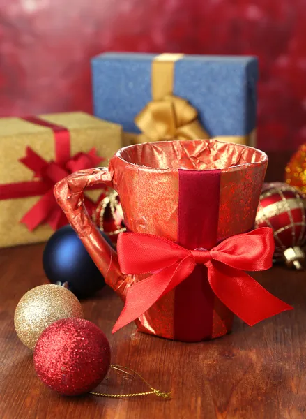 Tasse in Geschenkpapier verpackt mit Geschenken auf Holztisch auf hellem Hintergrund — Stockfoto