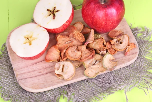 Manzanas secas, sobre tabla de cortar, sobre fondo de madera de color — Foto de Stock