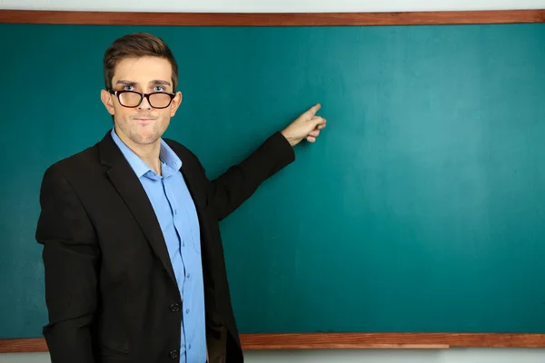 Young teacher near chalkboard in school classroom — Stock Photo, Image