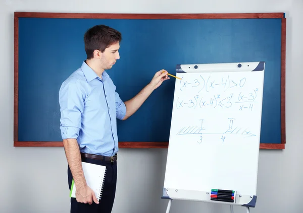 Young teacher near chalkboard in school classroom — Stock Photo, Image