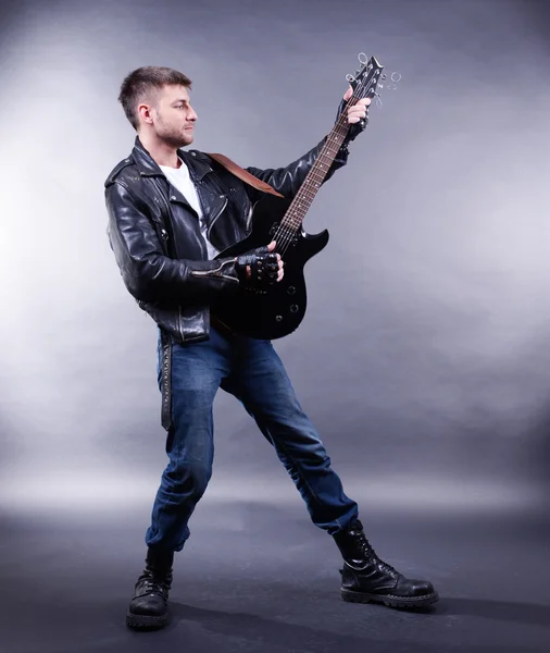 Junger Musiker spielt Gitarre auf grauem Hintergrund — Stockfoto