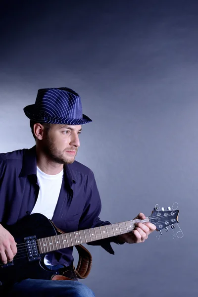 Joven músico tocando guitarra acústica y cantando, sobre fondo gris —  Fotos de Stock