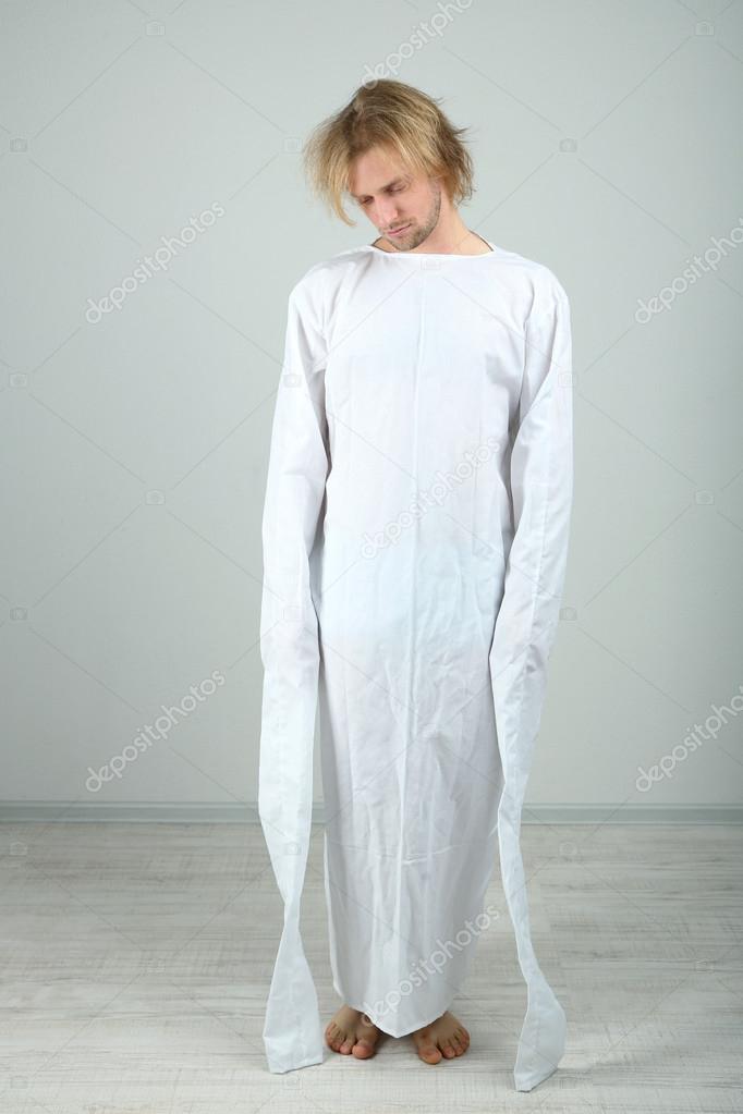 Mentally ill man in strait-jacket on gray background