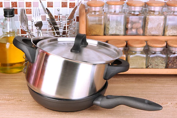 Pot et poêle dans la cuisine sur la table sur fond de carreaux de mosaïque — Photo