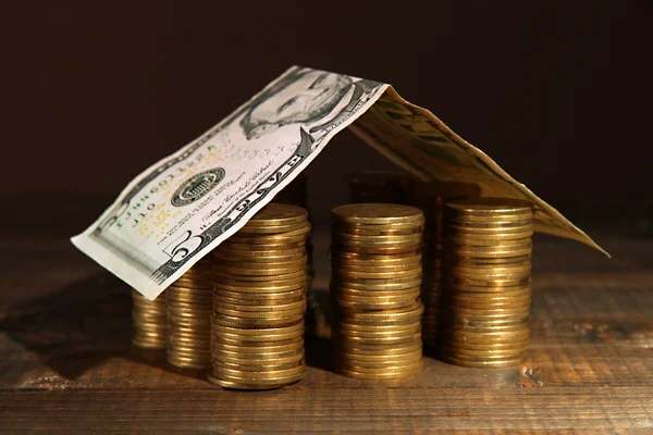 Coins house on table on brown background — Stock Photo, Image