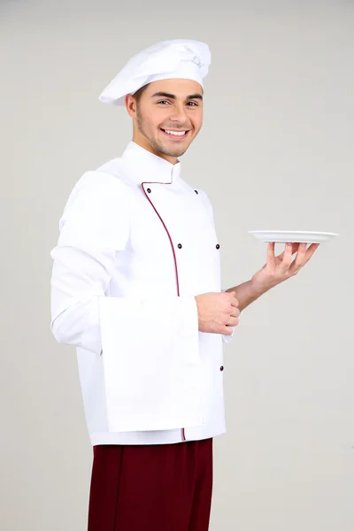 Chef profesional en uniforme blanco y sombrero, sobre fondo gris — Foto de Stock