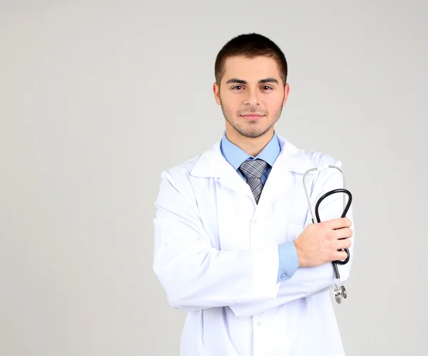 Male Doctor standing on gray background — Stock Photo, Image