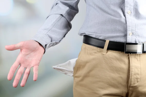 Homem mostrando seu bolso vazio no fundo brilhante — Fotografia de Stock