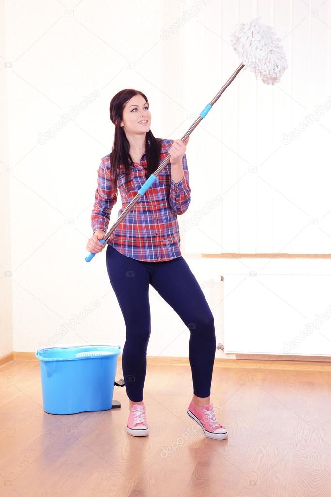 Young housewife with mop in room
