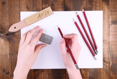 ahşap arka plan üzerinde sanat malzemeleri ile kalem tutan eller
