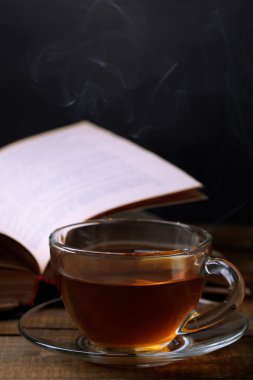 Tablodaki koyu arka plan üzerinde kitapla sıcak çay