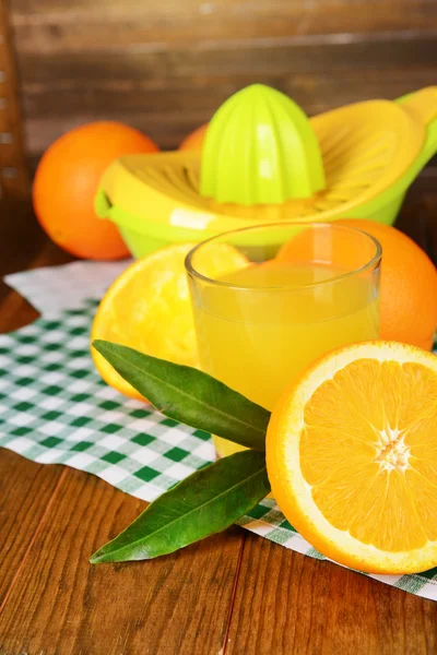 Цитрусових прес і апельсини на стіл з дерев'яними тлі — Stockfoto