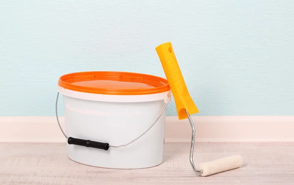 Paint and roll on floor in room on wall background — Stock Photo, Image