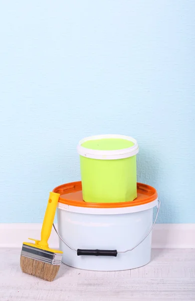 Paints and paintbrush on floor in room on wall background — Stock Photo, Image