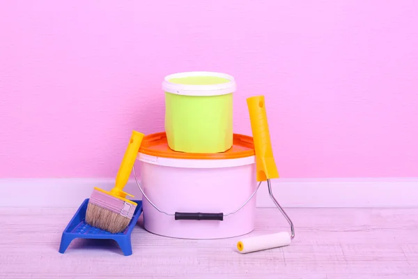 Tintas, rolo e pincel no chão no quarto no fundo da parede — Fotografia de Stock