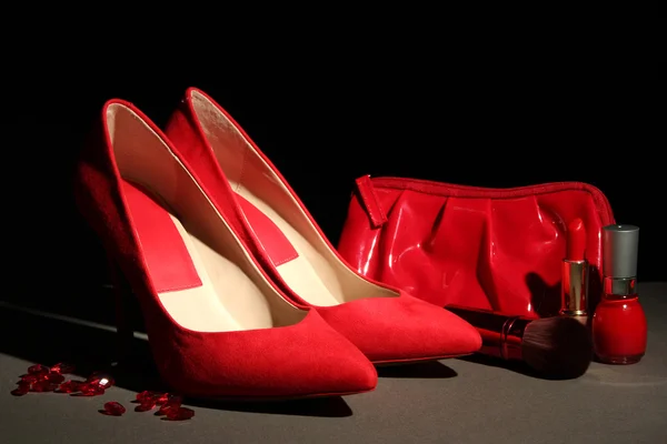 Belle scarpe rosse femminili e cosmetici, su sfondo nero — Foto Stock