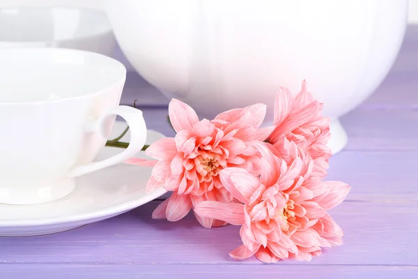 Crisantemos rosados con servicio de té sobre mesa de madera —  Fotos de Stock