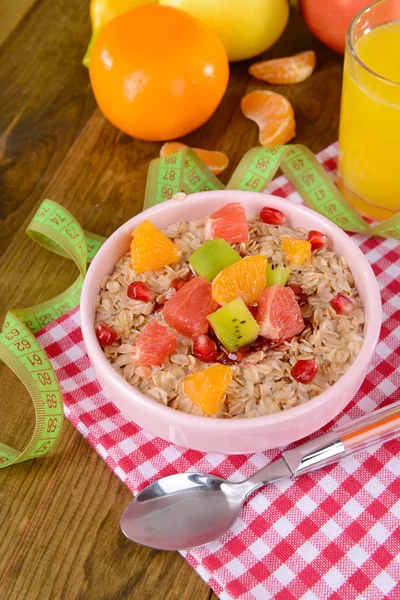 Deliciosa harina de avena con fruta en tazón en primer plano de la mesa —  Fotos de Stock