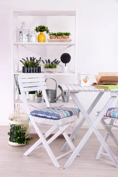 Chaises de jardin et table avec des fleurs sur des étagères sur fond blanc — Photo