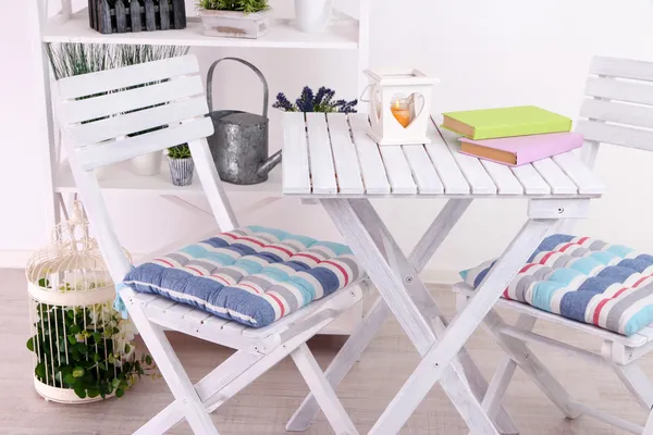 Garden chairs and table with flowers on shelves on white background — Stock Photo, Image