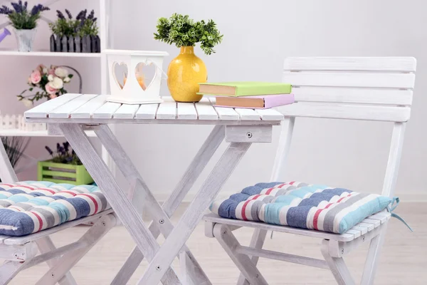 Cadeiras de jardim e mesa com flores nas prateleiras no fundo branco — Fotografia de Stock