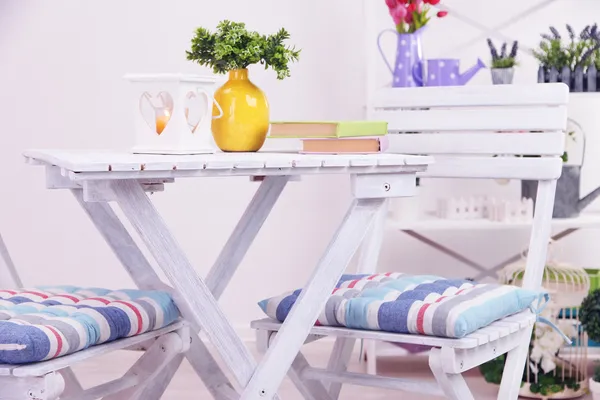 Sillas de jardín y mesa con flores en estantes sobre fondo blanco — Foto de Stock