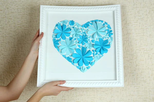 Mujer colgando cuadro con corazón de flores de papel — Foto de Stock