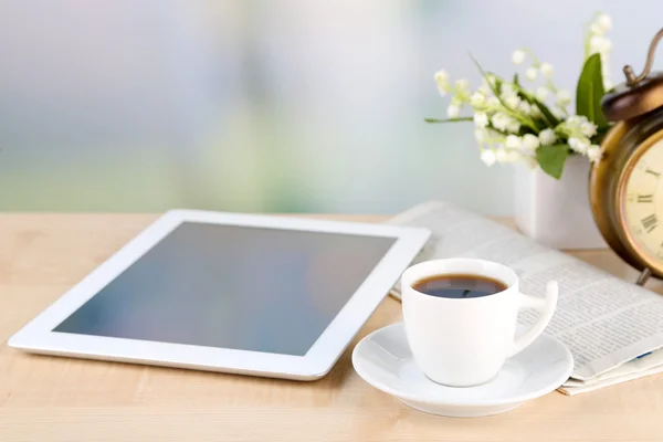Tableta, periódico, taza de café y despertador en mesa de madera — Foto de Stock