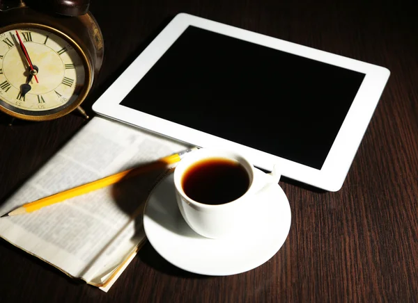 Tablet, newspaper, cup of coffee and alarm clock on wooden table — Stock Photo, Image