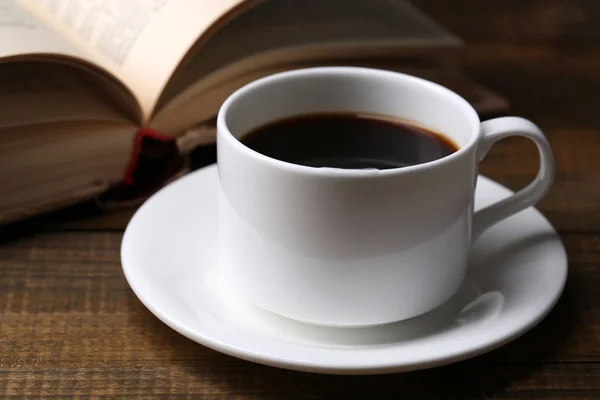 Kop warme koffie met boek op houten achtergrond — Stockfoto