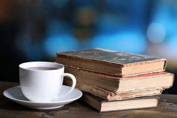 Xícara de chá quente com livros na mesa sobre fundo brilhante — Fotografia de Stock